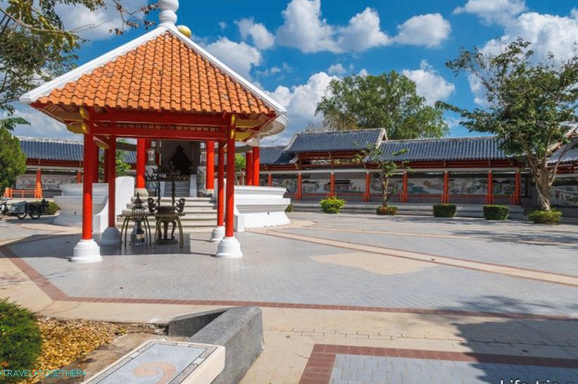 Skulptura kineskog božanstva ispod krova i zida uz park, sa slikama na pločici